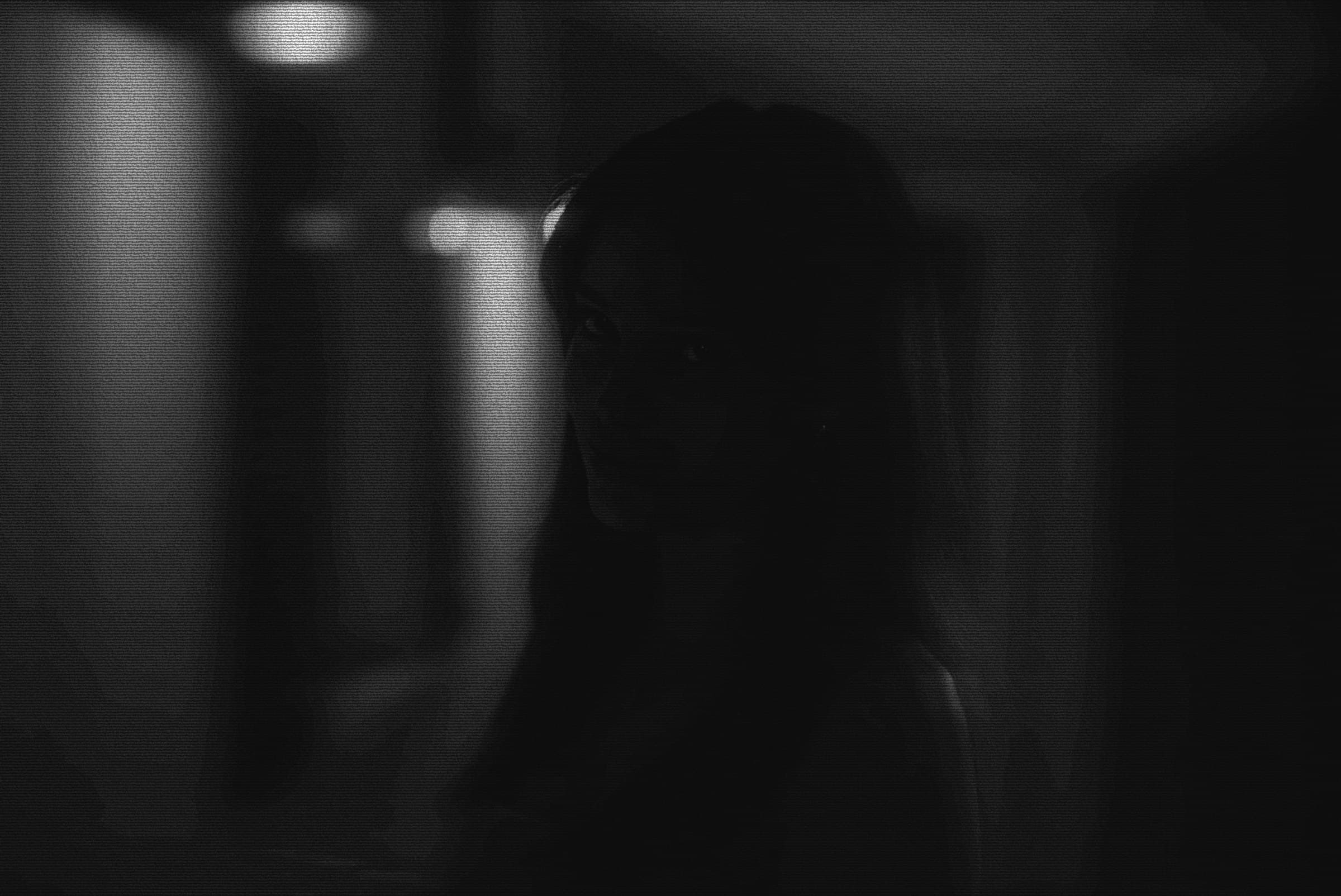 Nikki Freeman in heavily grained black-and-white, silhouetted in a backlit hallway.