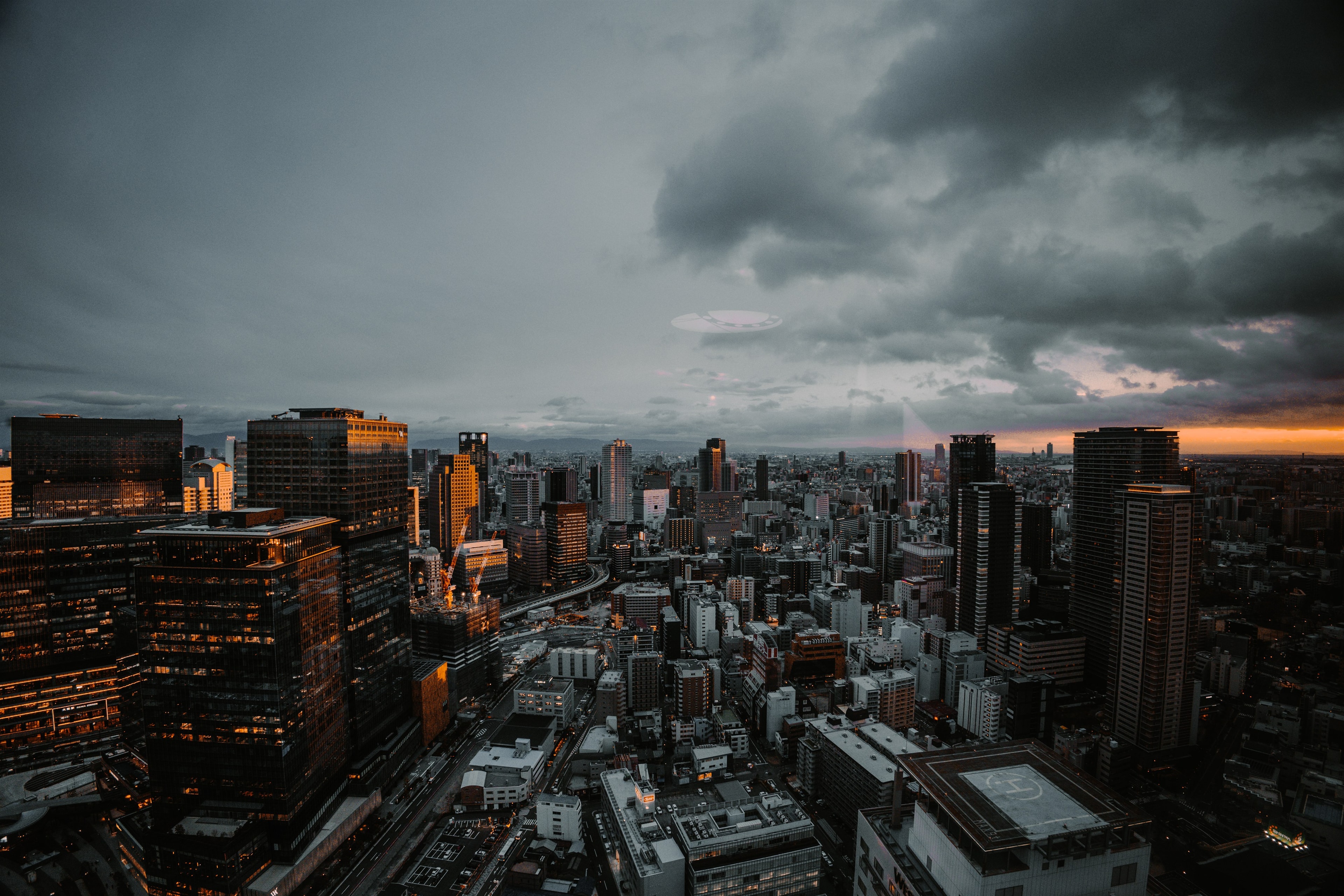 Osaka's skyline fading into dusk, storm light breaking gold along the horizon.