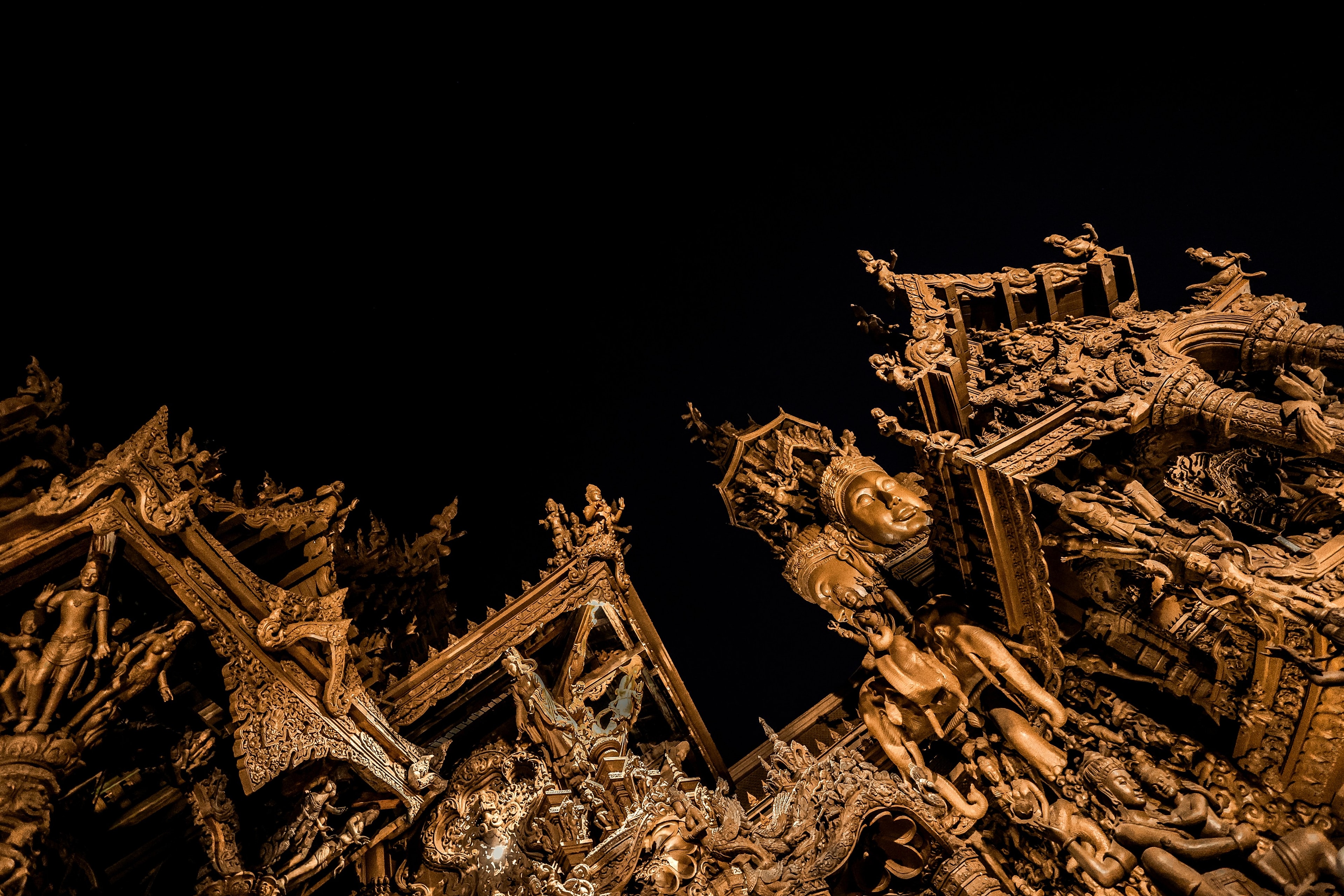 Close on the wooden carving of the Sanctuary of Truth, figures layered into the spire against a black sky.
